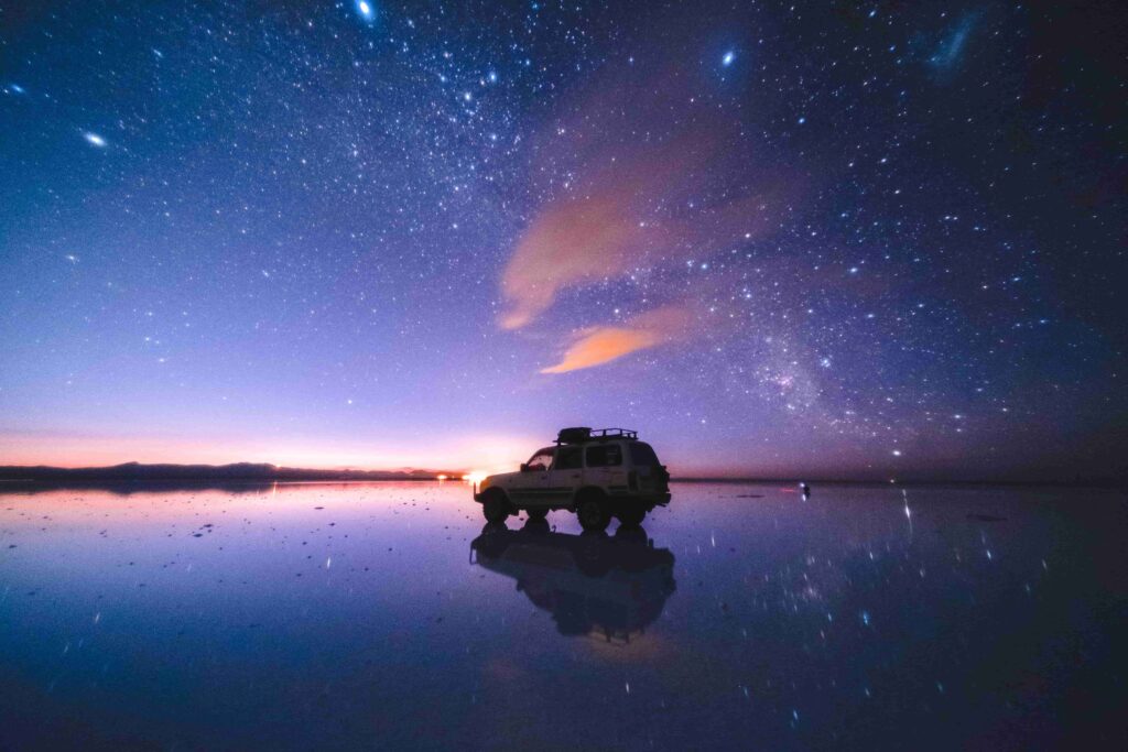 Carro parado no Salar de Uyuni durante uma noite estrelada.