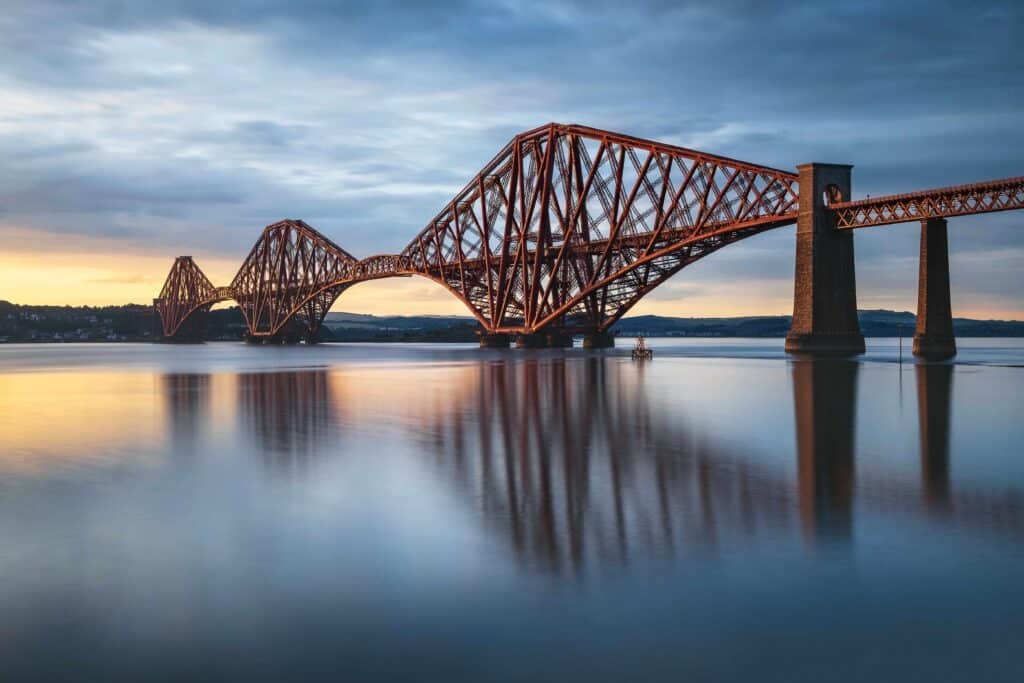 Vista da Forth Rail Bridge na ponte ferroviária do pôr do sol sobre Firth of Forth, perto de Queensferry, na Escócia