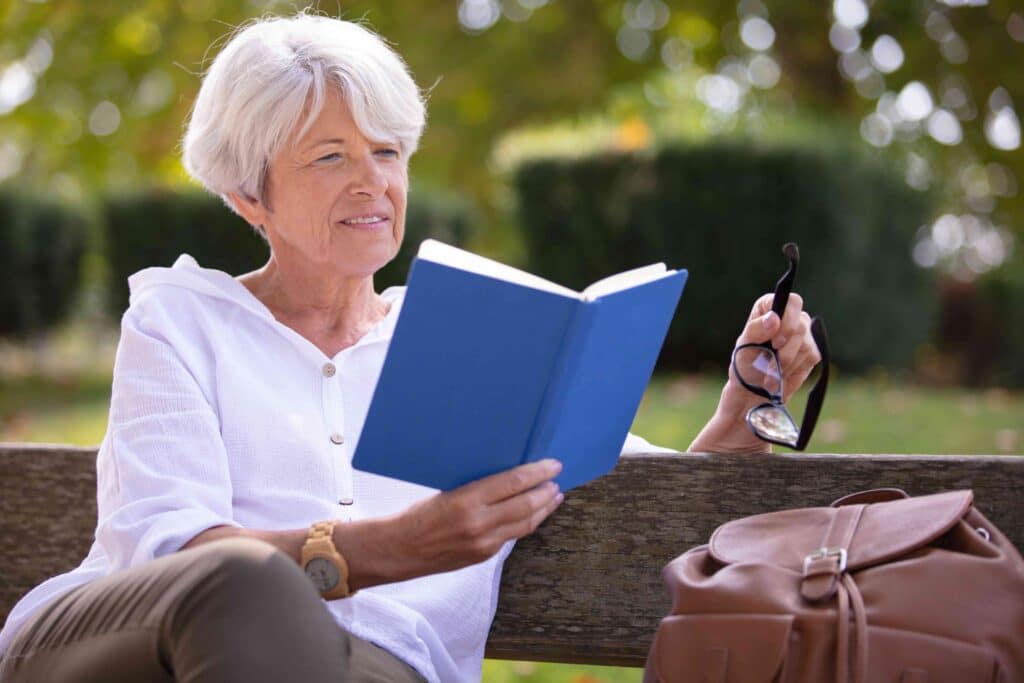 Mulher aposentada lê o livro de Gabriel García Márquez no parque.